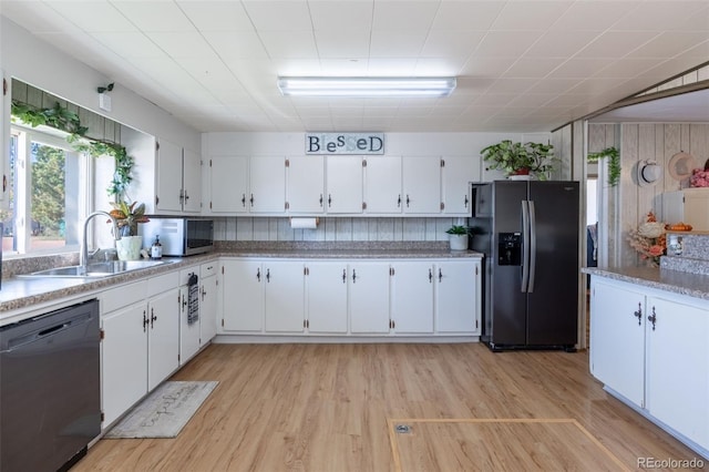 kitchen with appliances with stainless steel finishes, light wood-type flooring, a sink, and white cabinets