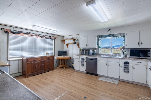 kitchen featuring dishwashing machine, light wood-style flooring, a sink, white cabinetry, and stainless steel microwave