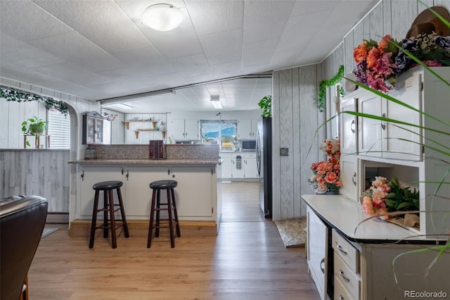 kitchen featuring light wood-style flooring, a kitchen breakfast bar, a peninsula, stainless steel appliances, and white cabinetry