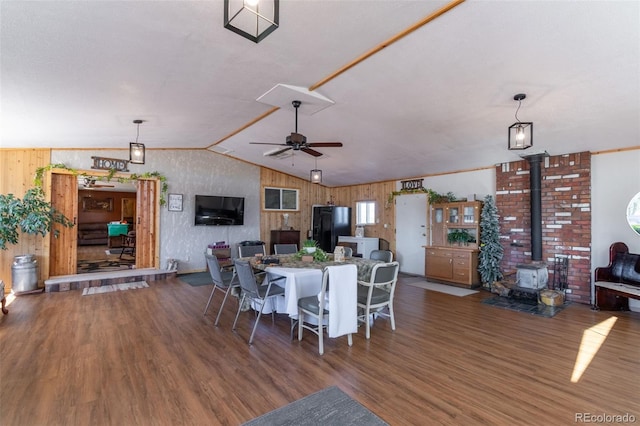 dining space featuring lofted ceiling, a wood stove, ceiling fan, and wood finished floors