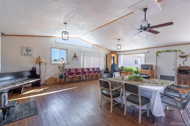 dining area featuring a ceiling fan, vaulted ceiling, a textured ceiling, and wood finished floors