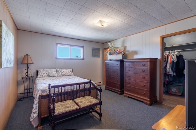 bedroom with a spacious closet, baseboard heating, carpet, and a closet