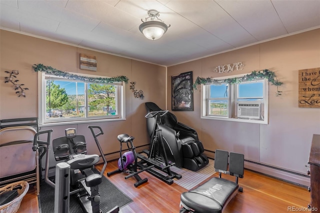 exercise room featuring a baseboard heating unit, cooling unit, a healthy amount of sunlight, and wood finished floors