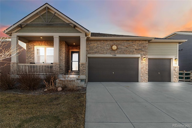 craftsman-style home featuring a garage, stone siding, covered porch, and concrete driveway