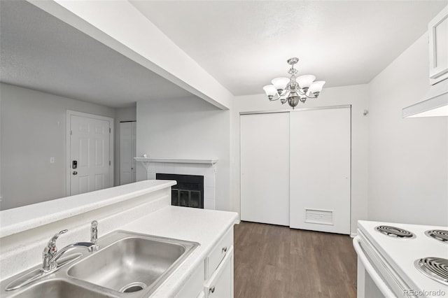 6705 S Field St Unit 803, Littleton, CO 80128 - kitchen featuring white cabinets, light countertops, a chandelier, dark wood-style floors, and a glass covered fireplace