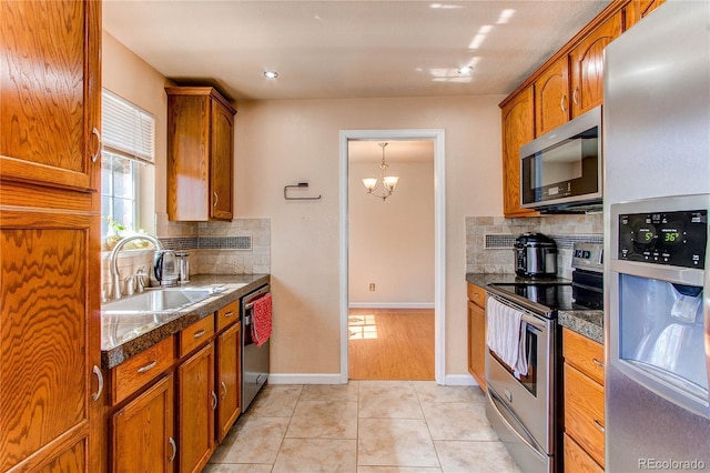 kitchen featuring light tile patterned floors, appliances with stainless steel finishes, a sink, and brown cabinets