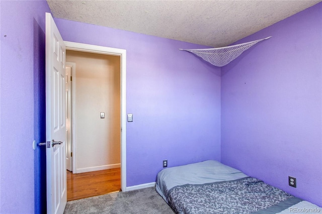 carpeted bedroom featuring a textured ceiling and baseboards