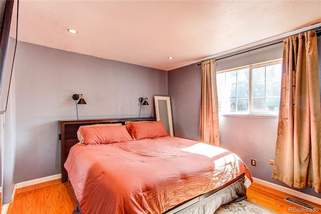 bedroom featuring visible vents, baseboards, wood finished floors, and recessed lighting