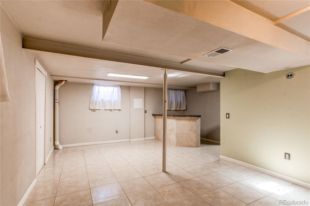 below grade area with visible vents, baseboards, and light tile patterned flooring