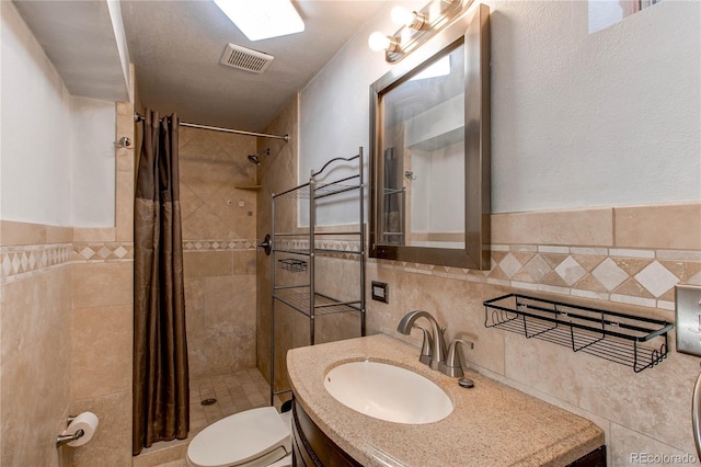 full bath featuring toilet, a tile shower, visible vents, and tile walls