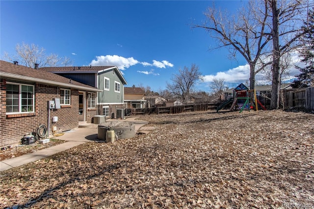 view of yard featuring a patio area, a fenced backyard, and a playground