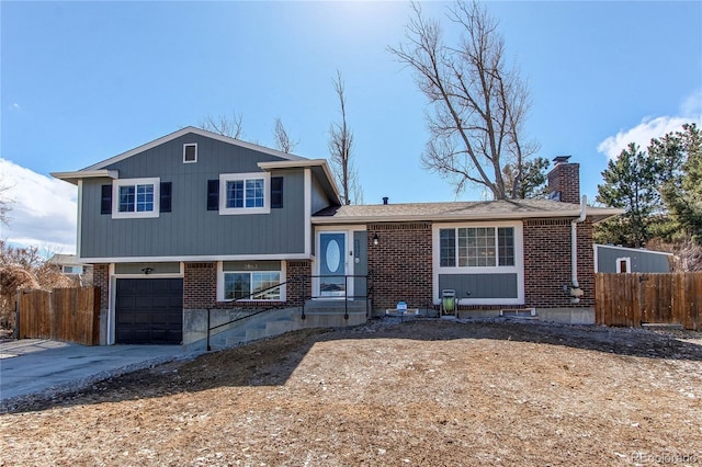 split level home with brick siding, a chimney, and fence