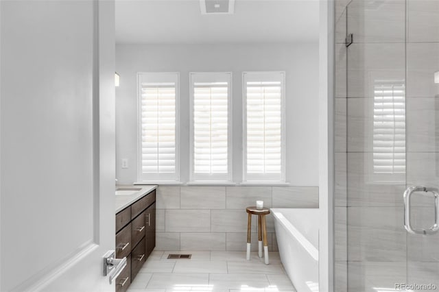 bathroom featuring a stall shower, tile patterned flooring, vanity, a soaking tub, and tile walls