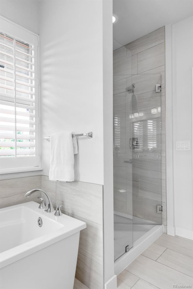 bathroom with a shower stall and a freestanding tub