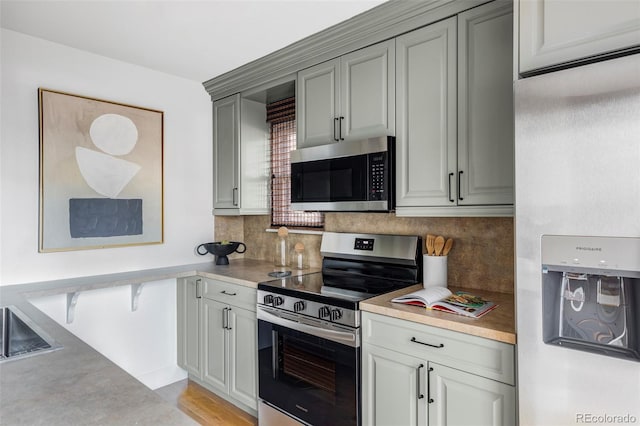 kitchen featuring decorative backsplash, light wood-type flooring, stainless steel appliances, and gray cabinets