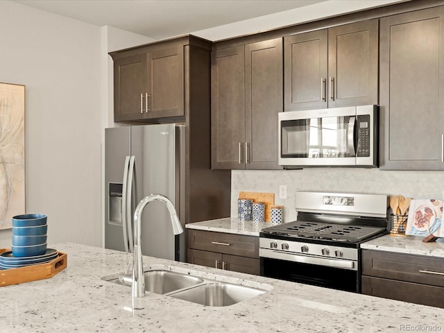 20802 E 66th Ave, Aurora, CO 80019 - kitchen featuring appliances with stainless steel finishes, a sink, dark brown cabinets, and light stone countertops