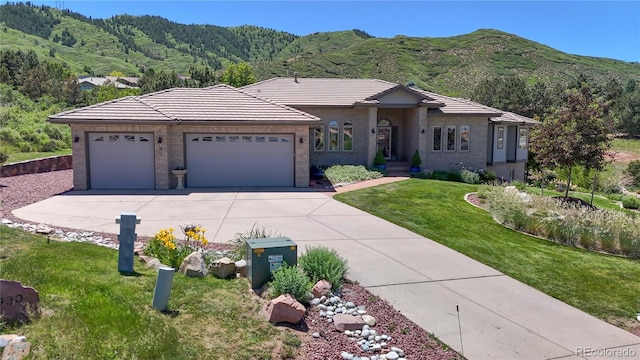 view of front of house featuring a mountain view, concrete driveway, an attached garage, and a tiled roof