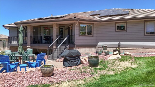 rear view of property with a patio area, solar panels, and a tiled roof