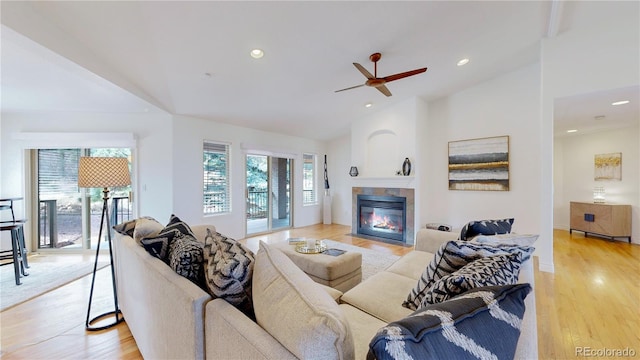 living room with a tile fireplace, recessed lighting, light wood finished floors, baseboards, and vaulted ceiling