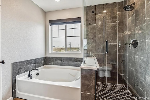 bathroom featuring a garden tub, a textured wall, a shower stall, and toilet