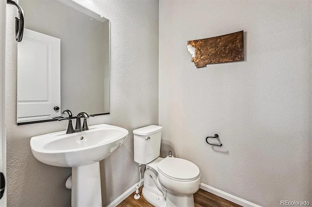 bathroom featuring baseboards, a textured wall, toilet, and wood finished floors