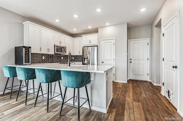 kitchen with a peninsula, dark wood-style floors, a kitchen bar, and stainless steel appliances