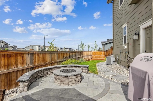 view of patio with a fire pit, a fenced backyard, a residential view, and central air condition unit