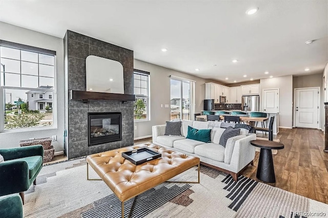 living area with a fireplace, baseboards, wood finished floors, and recessed lighting