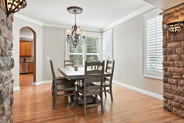 7809 S Coolidge Way, Aurora, CO 80016 - dining space featuring arched walkways, a chandelier, healthy amount of natural light, light wood-style floors, and ornamental molding