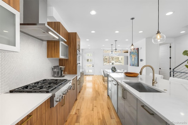 kitchen with wall chimney exhaust hood, modern cabinets, pendant lighting, and light countertops