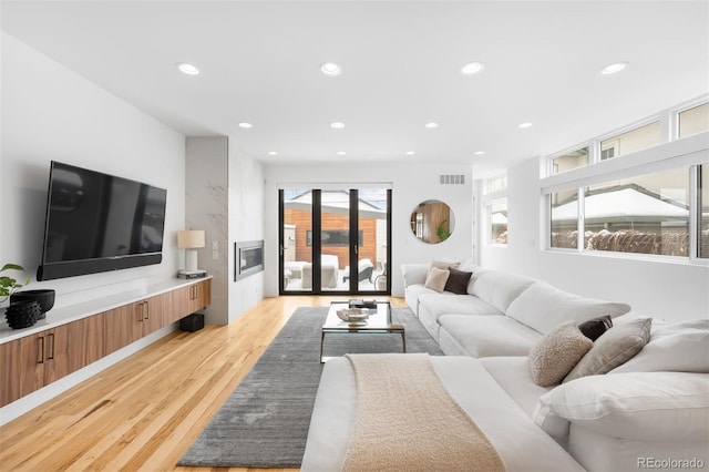 living area with light wood-style flooring, visible vents, and recessed lighting