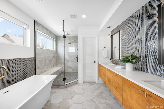 bathroom featuring tile patterned flooring, a sink, tile walls, a shower stall, and double vanity