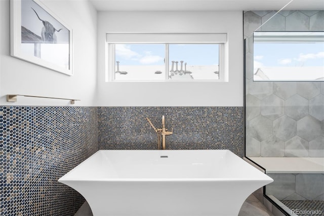 full bathroom featuring a soaking tub, a wainscoted wall, a sink, and tile walls