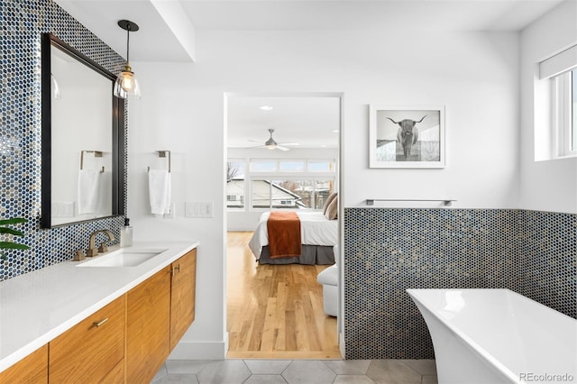 bathroom featuring tile walls, a soaking tub, connected bathroom, vanity, and tile patterned flooring