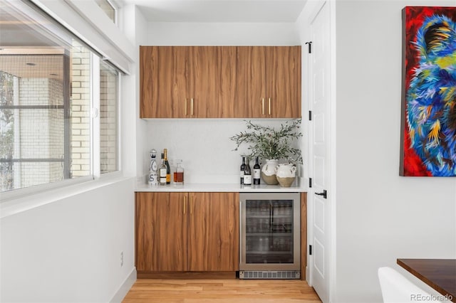 bar with a dry bar, light wood finished floors, and wine cooler