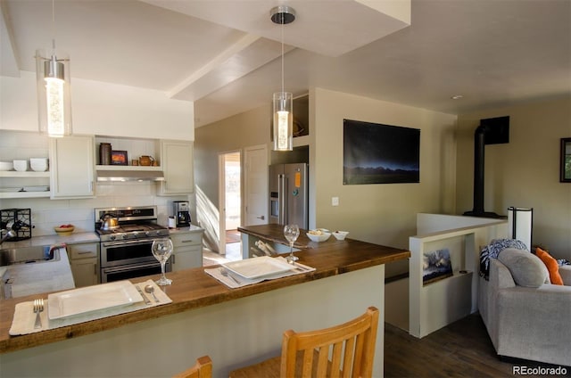 kitchen with kitchen peninsula, tasteful backsplash, butcher block countertops, decorative light fixtures, and appliances with stainless steel finishes