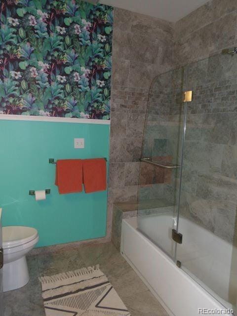 bathroom with bath / shower combo with glass door, tile patterned flooring, and toilet