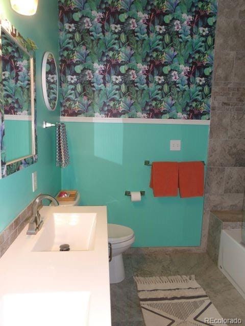 bathroom with tile patterned floors, a washtub, vanity, and toilet