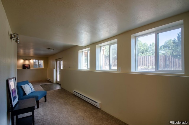 living area with a textured ceiling, carpet flooring, and a baseboard heating unit