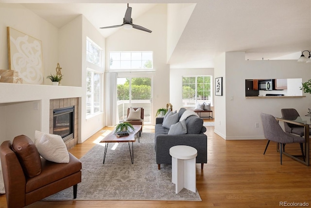 805 Summer Hawk Dr Unit 100, Longmont, CO 80504 - living area with wood finished floors, a tile fireplace, a ceiling fan, baseboards, and a towering ceiling