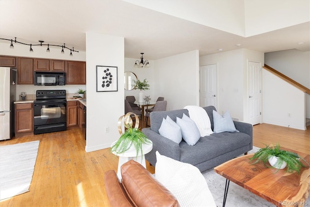 805 Summer Hawk Dr Unit 100, Longmont, CO 80504 - living area with a chandelier, light wood-type flooring, baseboards, and stairway