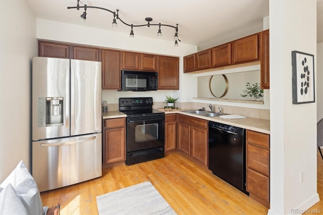 805 Summer Hawk Dr Unit 100, Longmont, CO 80504 - kitchen featuring black appliances, a sink, light countertops, light wood-style flooring, and brown cabinets