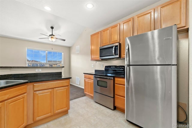 kitchen featuring lofted ceiling, sink, ceiling fan, dark stone countertops, and appliances with stainless steel finishes