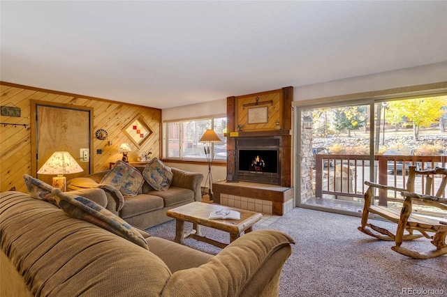 carpeted living room featuring a fireplace and wooden walls