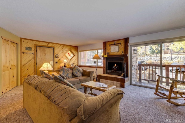 carpeted living room featuring a tile fireplace, wood walls, and a textured ceiling