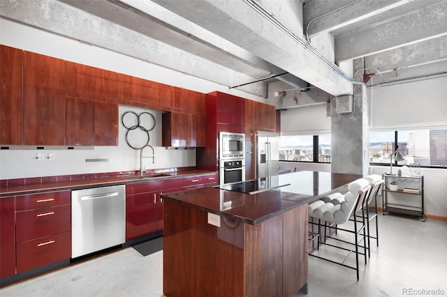 kitchen featuring stainless steel appliances, a kitchen island, a kitchen breakfast bar, and sink