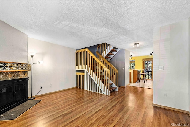 1209 S Flower Cir Unit C, Lakewood, CO 80232 - unfurnished living room with a tile fireplace, stairway, wood finished floors, baseboards, and a textured ceiling