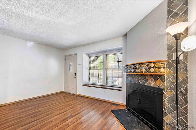 1209 S Flower Cir Unit C, Lakewood, CO 80232 - unfurnished living room featuring a tiled fireplace, wood finished floors, a textured ceiling, and baseboards