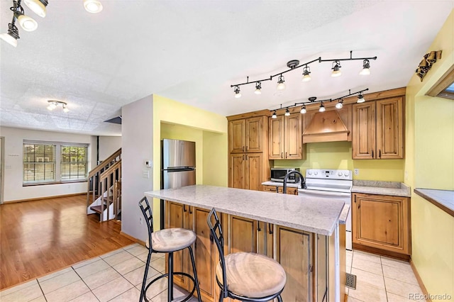 1209 S Flower Cir Unit C, Lakewood, CO 80232 - kitchen featuring stainless steel appliances, light tile patterned flooring, a center island with sink, a kitchen bar, and baseboards