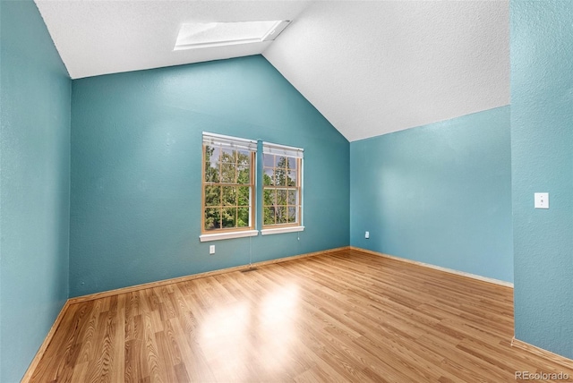 1209 S Flower Cir Unit C, Lakewood, CO 80232 - spare room featuring a skylight, vaulted ceiling, wood finished floors, and baseboards